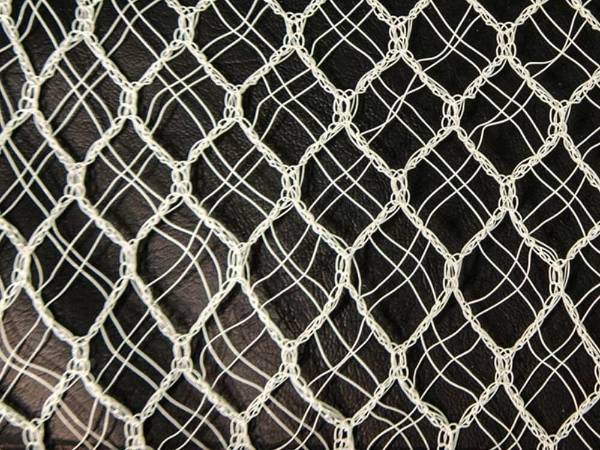 White Raschel quad crossover knitted hail netting on a black background