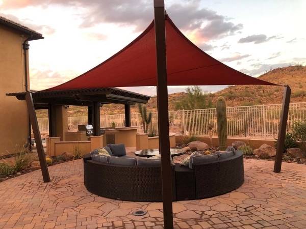 Red sun shade sail installed in a home yard