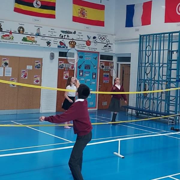 Players are playing the badminton in school indoor stadium.