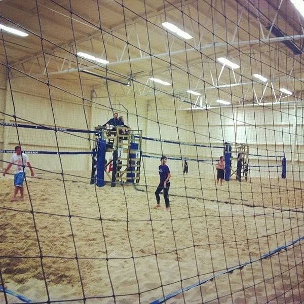 Players are playing beach volleyball game in the stadium.