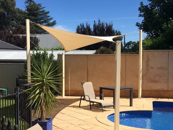 Square sun shade sail is attached to galvanized posts.